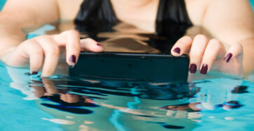 Kobieta w basenie trzya w wodzie swój wodoodporny telefon